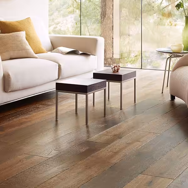 Living room with dark brown fumed oak planks from Veranda's Charleston collection in Sweet Tea beside tall windows (manufacturer room scene)