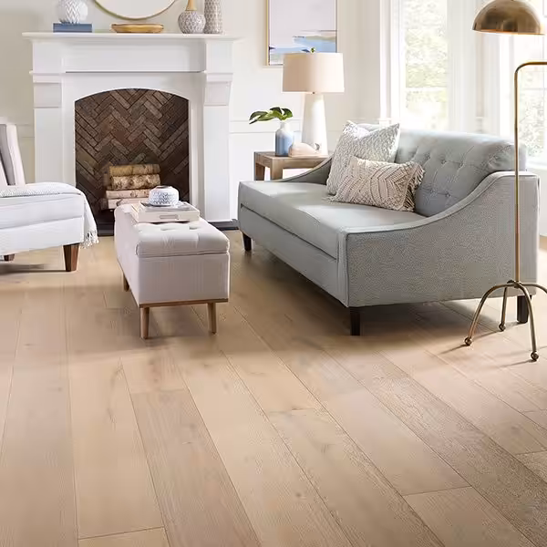 Veranda manufacturer room scene of Charleston collection engineered French oak in the Waterfront color, a light oak floor in a living room with a white fireplace and gray sofa