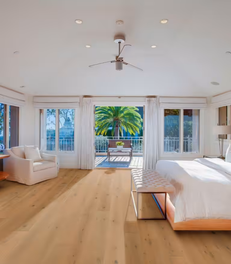 Bright bedroom with a tufted bench at the foot of the bed and wide, light European oak planks running to open balcony doors, Sienna River collection in Rhine (manufacturer photo)